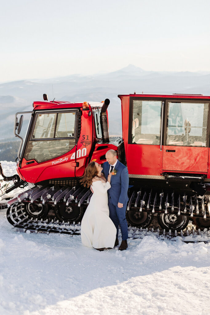 couple standing in front of a snow cat at their mt.hood elopement at silcox hut