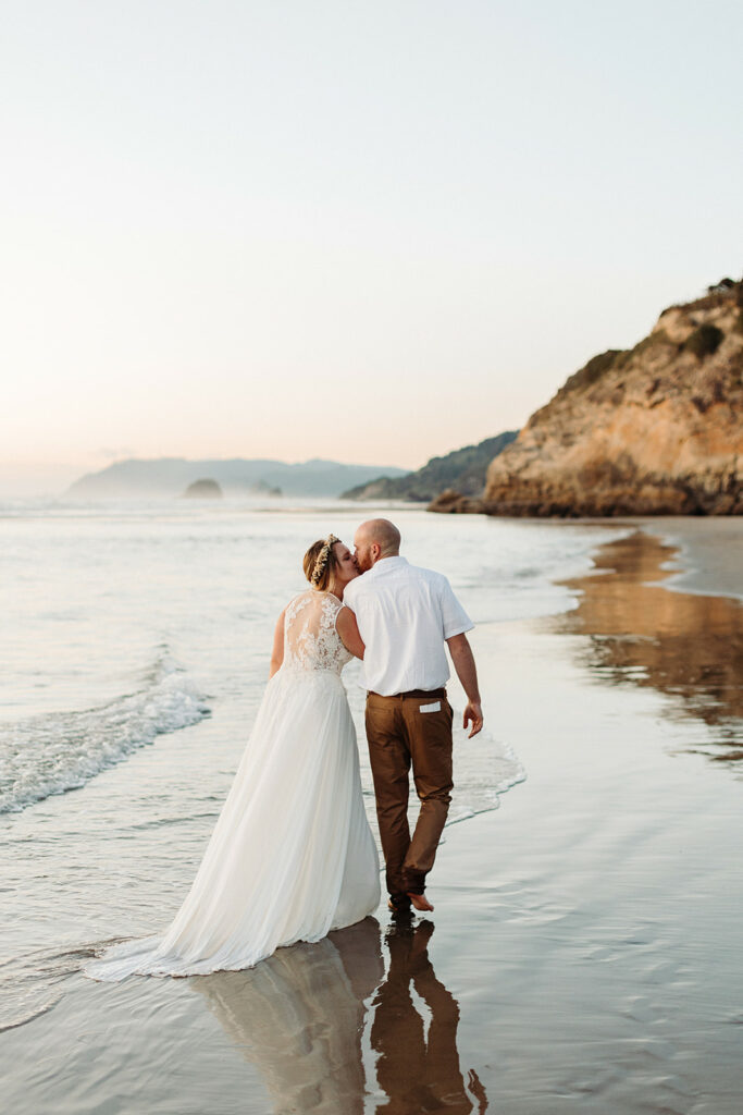 a newlywed couple walking on the oregon coast beach